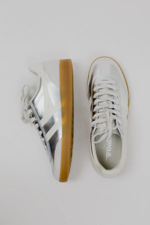 Pair of white sneakers with brown soles on a light gray background