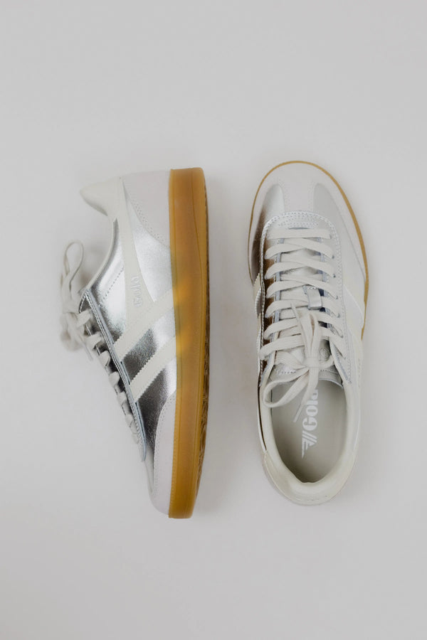 Pair of white sneakers with brown soles on a light gray background