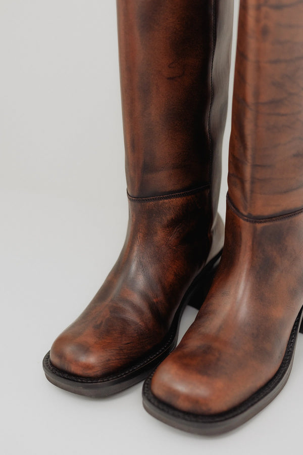 Pair of brown leather boots on a light gray background