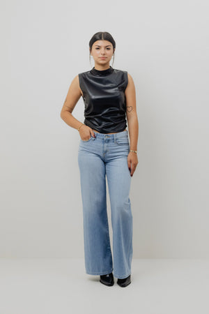 Person wearing a black sleeveless top and light blue jeans on a white background
