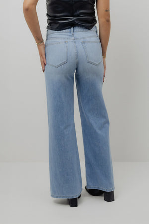 Person wearing light blue jeans on a plain background