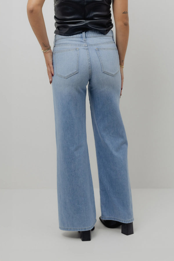 Person wearing light blue jeans on a plain background