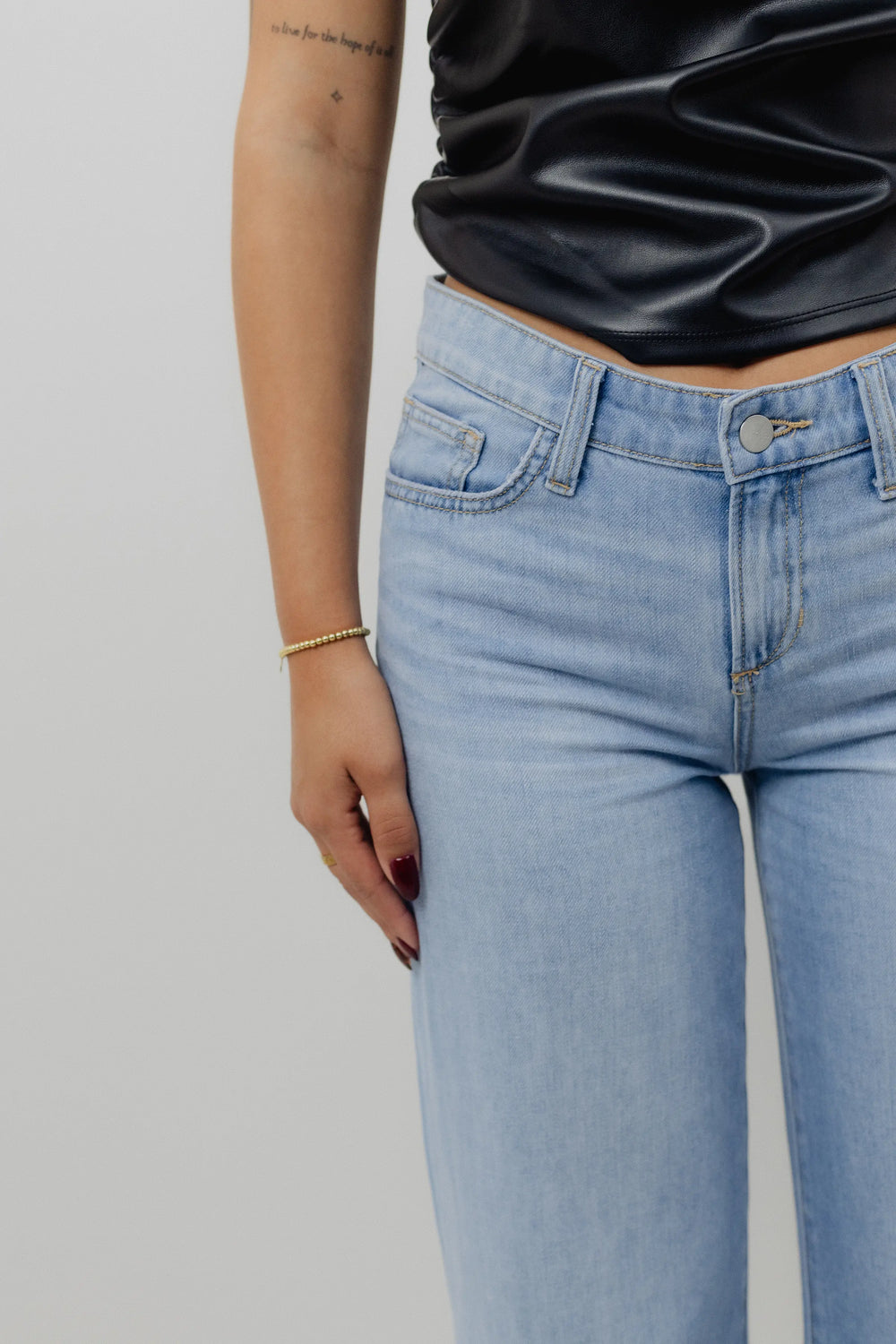 Person wearing light blue jeans and black shoes on a plain background