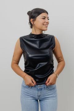 Woman wearing a black sleeveless top and blue jeans against a plain background