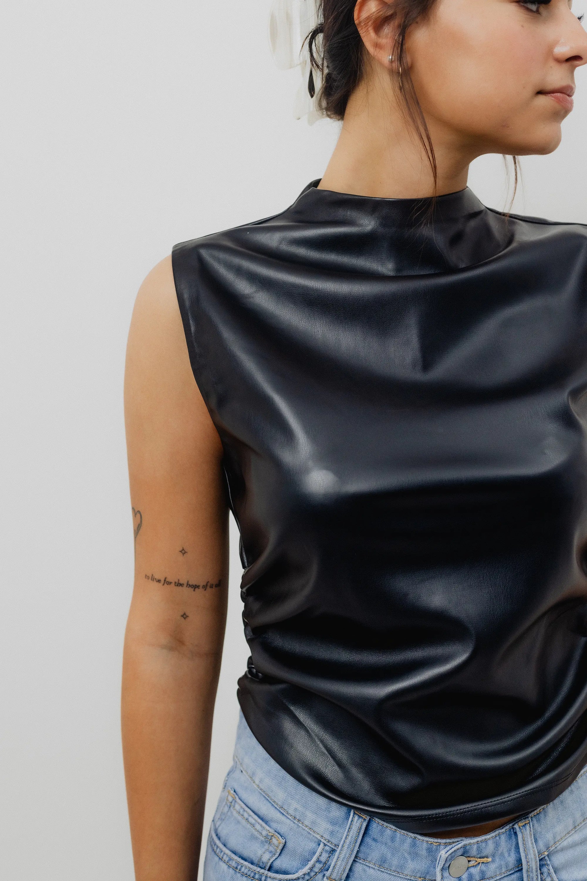 Person wearing a black sleeveless top with a plain background