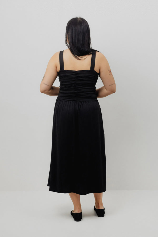 Woman wearing a black dress standing against a plain background