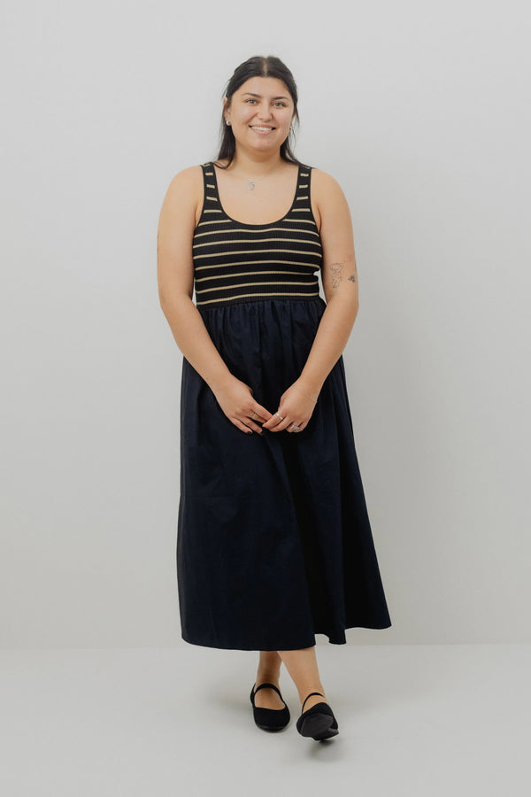 Woman wearing a black and gold striped tank top with a black skirt on a white background