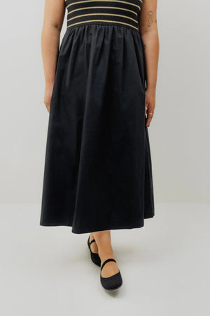 Person wearing a black dress with a striped top on a white background