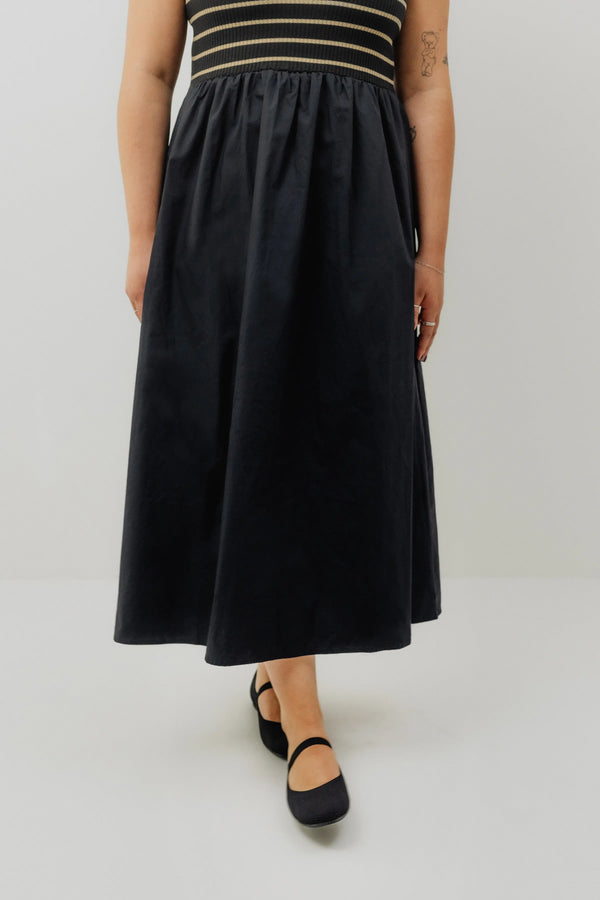 Person wearing a black dress with a striped top on a white background