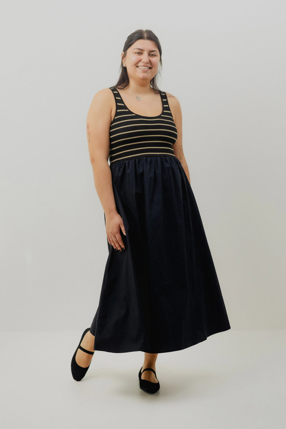 Woman wearing a black dress with a striped top on a white background