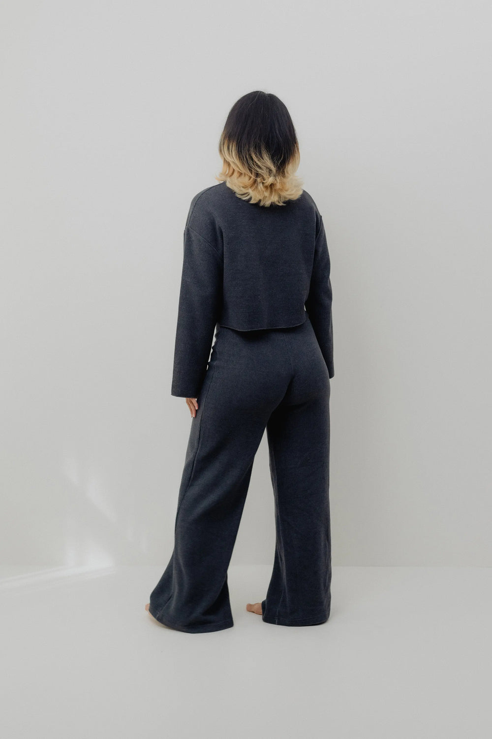 Woman wearing a dark blue outfit on a plain background