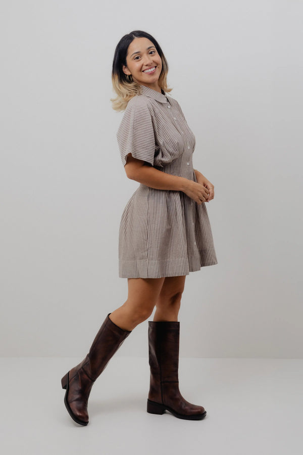 Woman wearing a plaid dress and brown knee-high boots on a white background