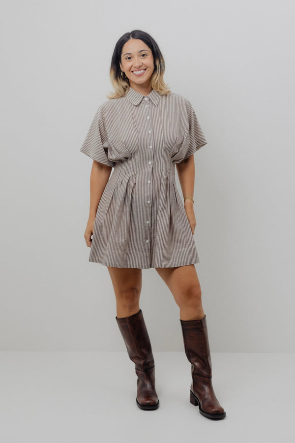 Woman wearing a checkered dress and brown boots against a white background