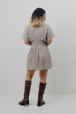 Woman wearing a patterned dress and knee-high boots on a plain background