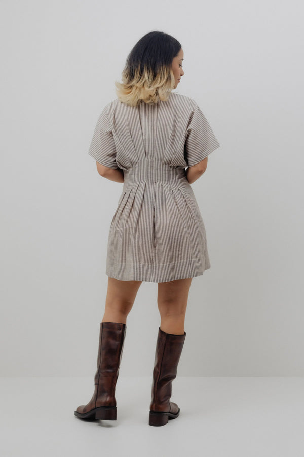 Woman wearing a patterned dress and knee-high boots on a plain background