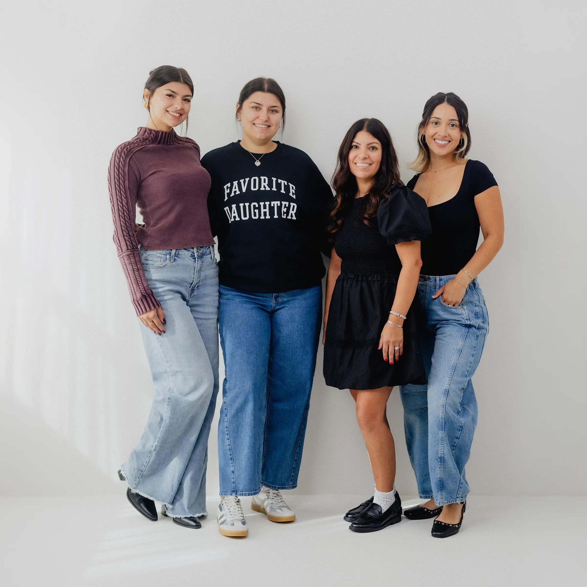 Four women posing together against a plain background