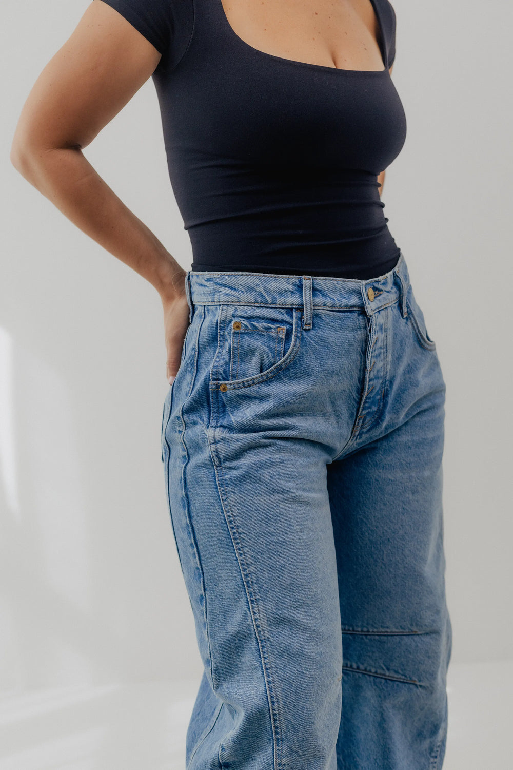 Person wearing blue wide-leg jeans and black shoes on a white background