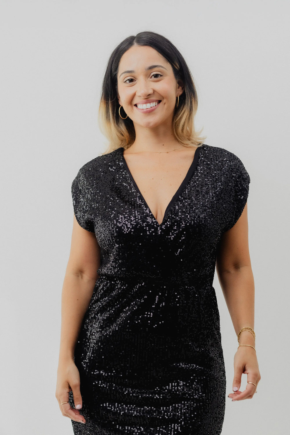 Woman wearing a black sequin dress against a plain background