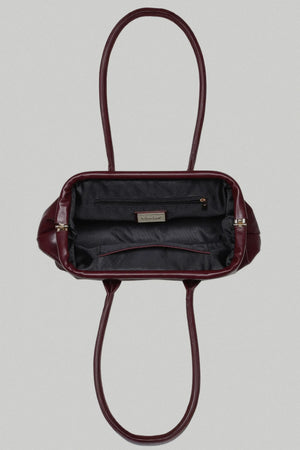 Burgundy handbag with open top on a light gray background