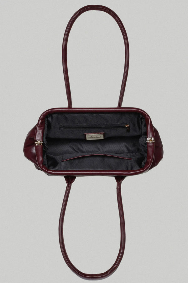 Burgundy handbag with open top on a light gray background