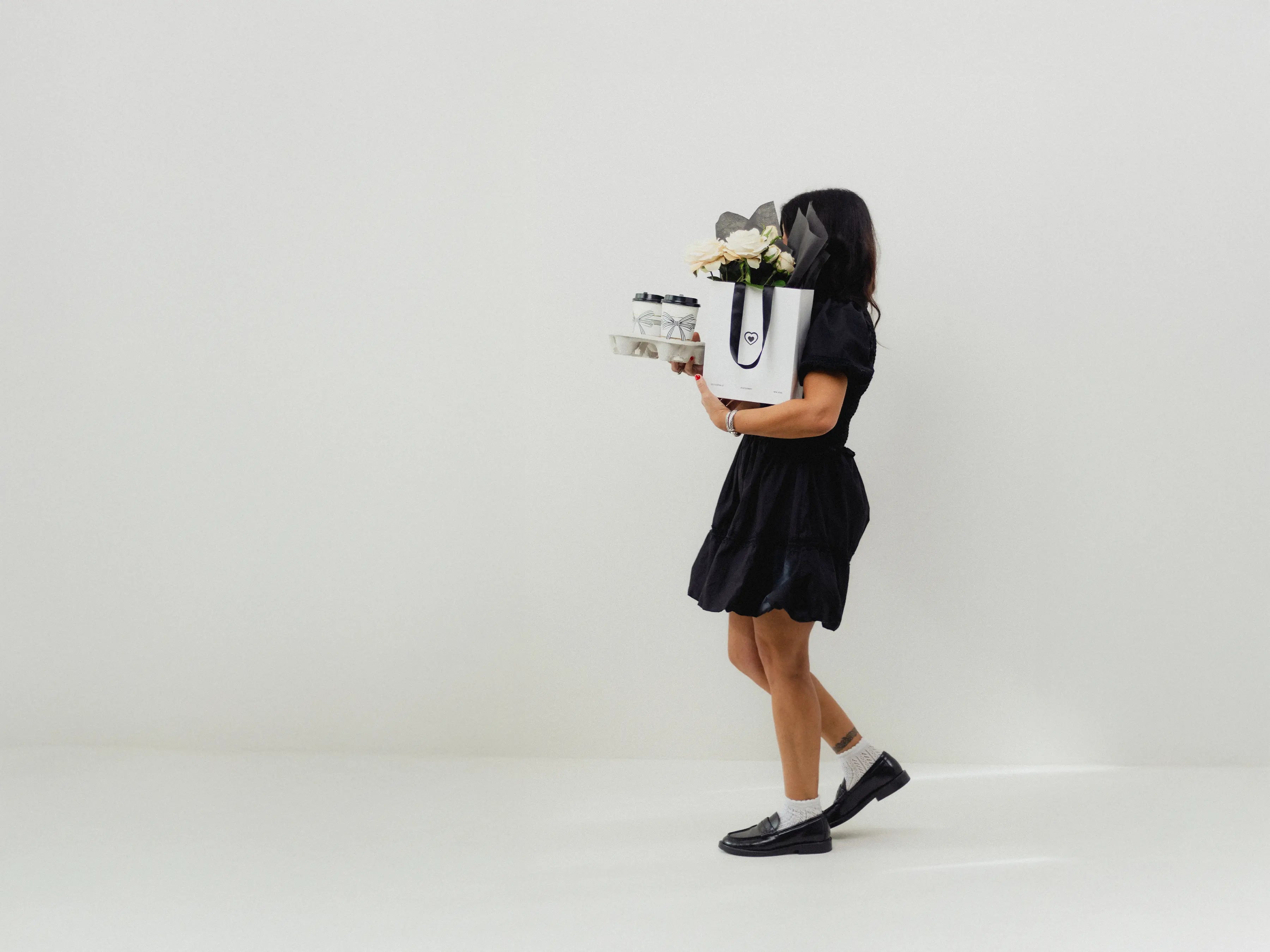 Person holding a white tote bag with flowers against a plain background