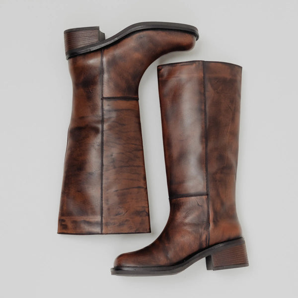 Pair of brown leather knee-high boots on a light gray background